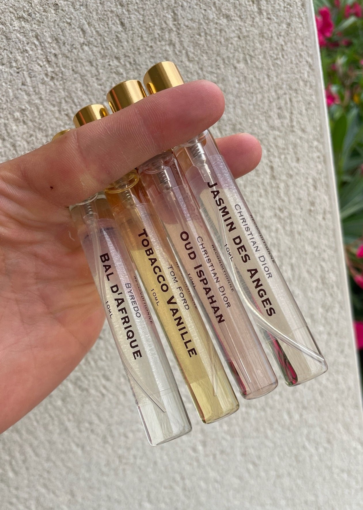 4 petits flacons décants CapitoleParfum dans la main du fabricant. Il y a Jasmin des Anges  et Oud Ispahan de Dior, Tobacco Vanille de Tom Ford, Bal d'Afrique Byredo