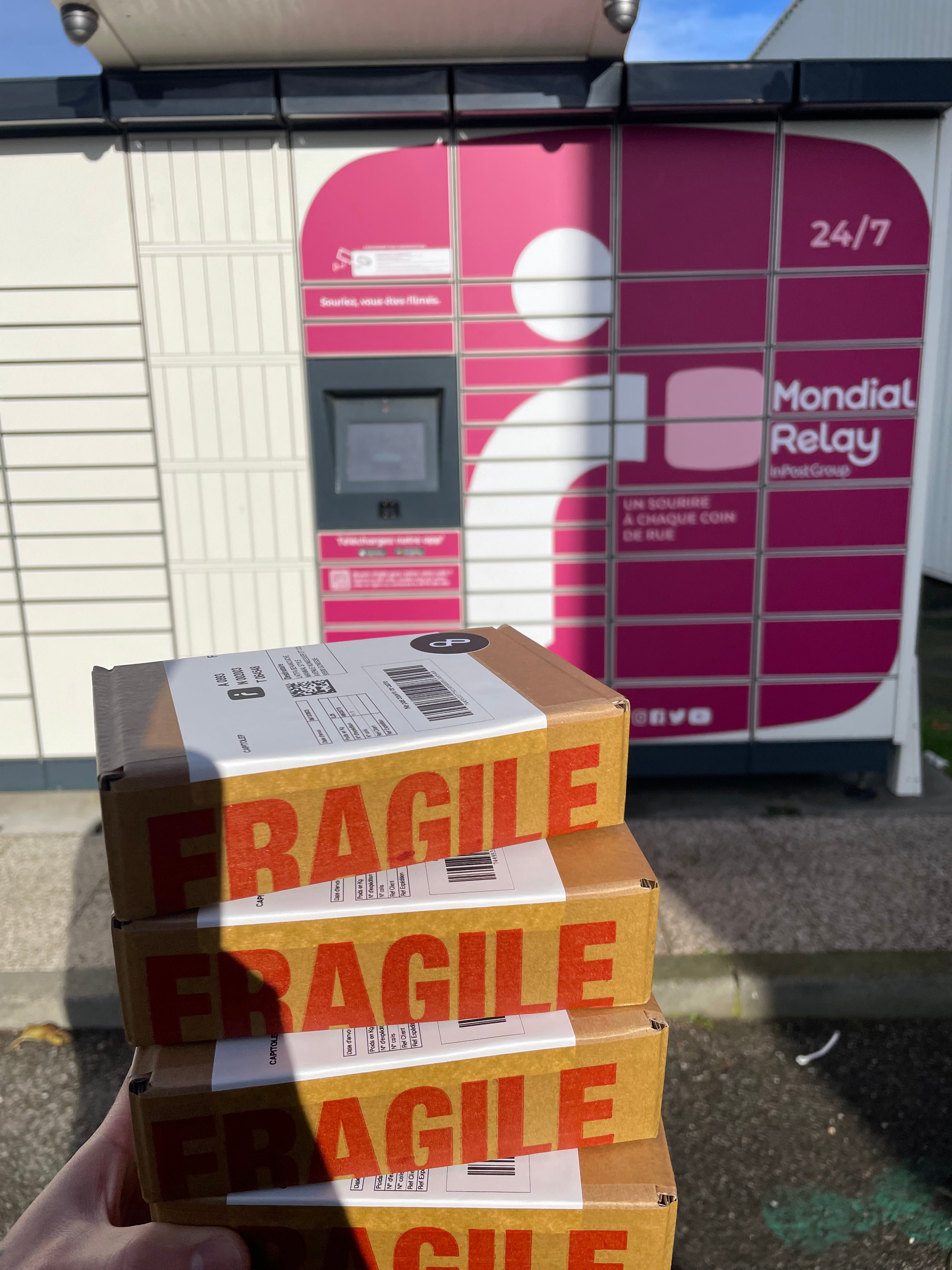 Quatre colis devant locker Mondial Relay en partance pour des clients CapitoleParfum contenants des commandes de petits flacons de parfums originaux aussi appelés décants