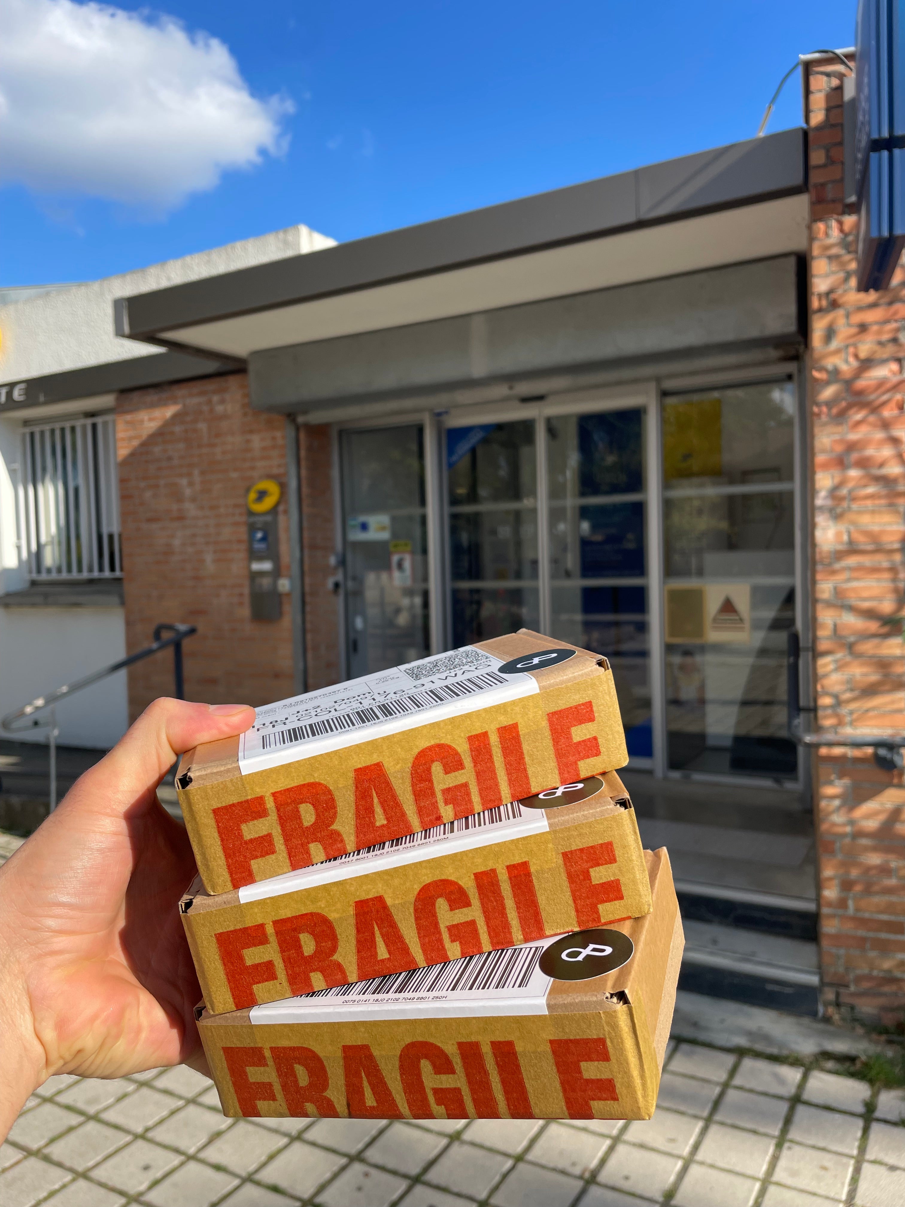 Trois colis de décants CapitoleParfum avant d'être postés. Journée ensoleillée. La Poste. 